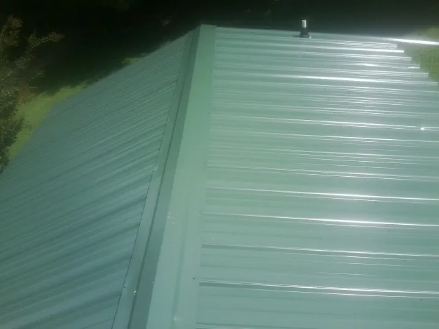 New green metal panels meeting at the ridge of a roof — Flat Roof Repair work by our crew in Sale City