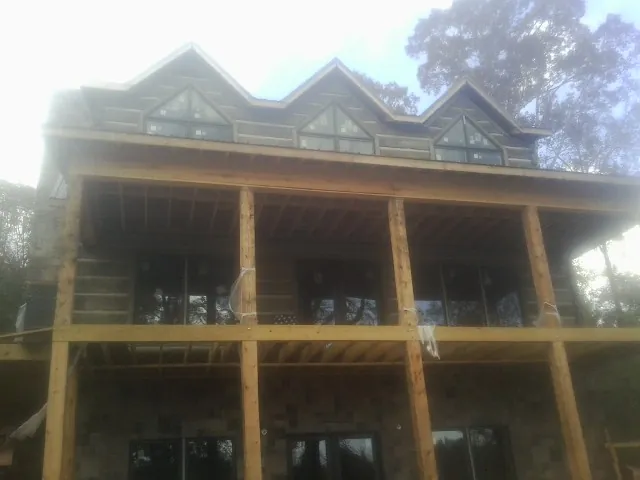 Dormers and porch framing on a large log home under construction — Roof Coating work by our crew in Sale City