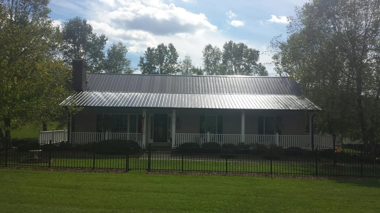 Gray metal roof on a brick ranch with a full width front porch — Gutter Guard Installation work by our crew in Sale City