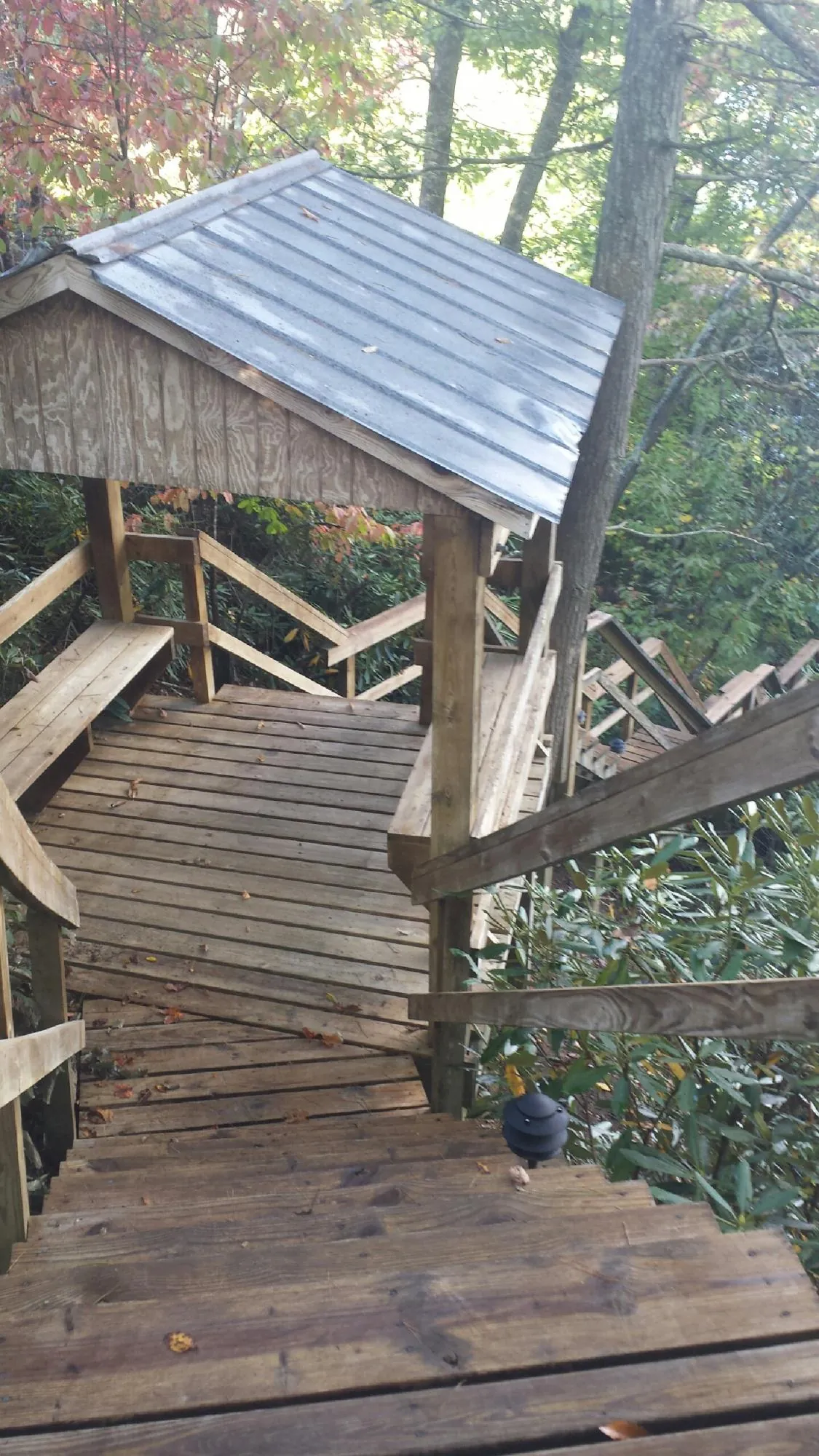 Metal roofed shelter over wooden steps on a wooded walkway — Skylight Repair & Installation work by our crew in Sale City
