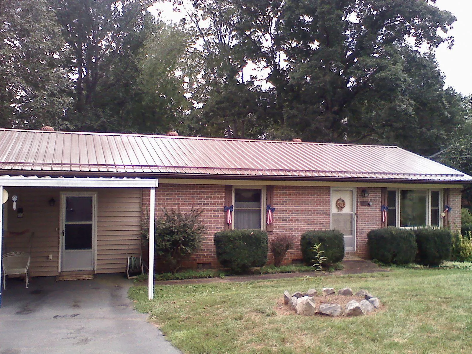 Bronze metal roof and carport on a brick ranch home — Roof Repair work by our crew in Sale City