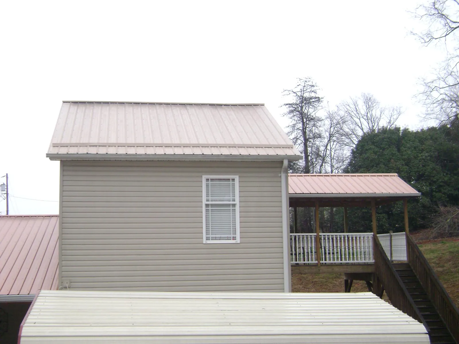 Tan metal roofs on a two story addition and attached porch, from a Roof Replacement job in Sale City