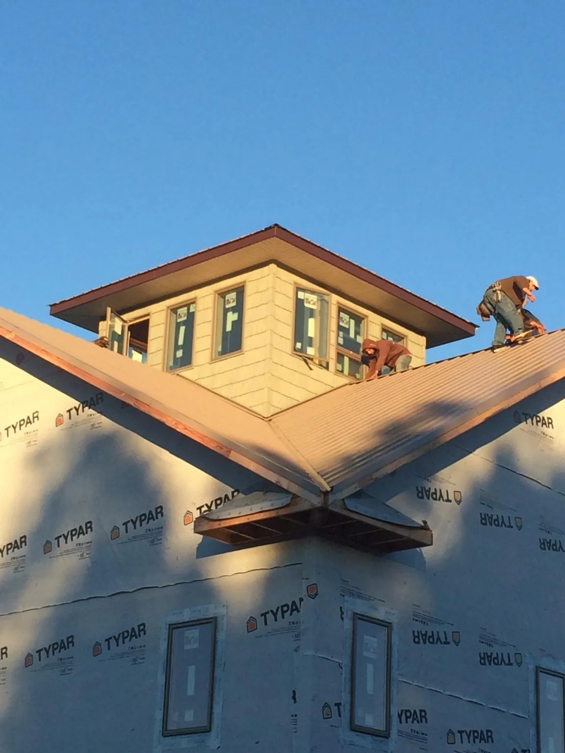 Roofers working around a rooftop cupola on a new metal roof at sunset — Roof Waterproofing in Sale City by Roofing Brothers